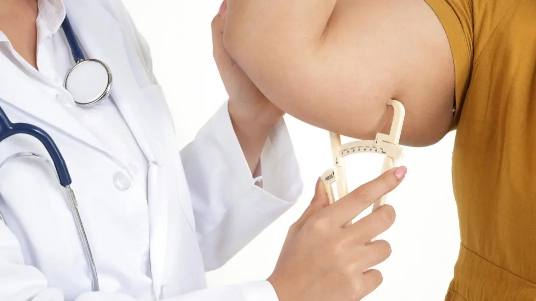 un medico che prende le misure del braccio di un paziente obeso per determinare la sua idoneità ai trattamenti farmacologici e nutrizionali
