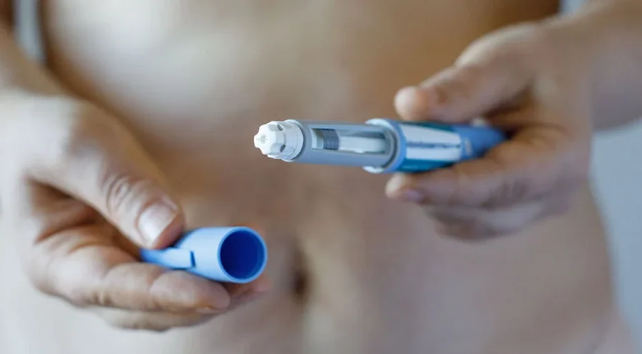 un uomo che stringe tra le mani una penna pre-riempita apertadi principio attivo glp-1 e gip