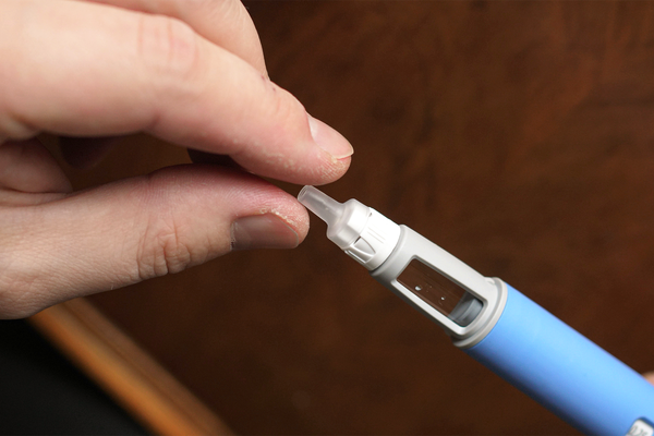 due dita che si stringono attorno all'estremità di una pennetta che contiene il principio attivo dei farmaci per dimagrire