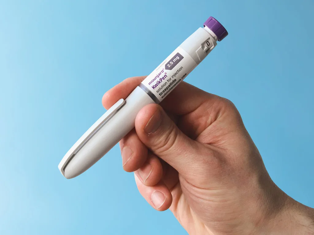 una mano che stringe una penna pre-riempita del farmaco mounjaro
