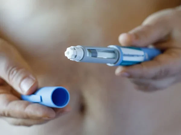 un uomo che stringe tra le mani una penna pre-riempita apertadi principio attivo glp-1 e gip