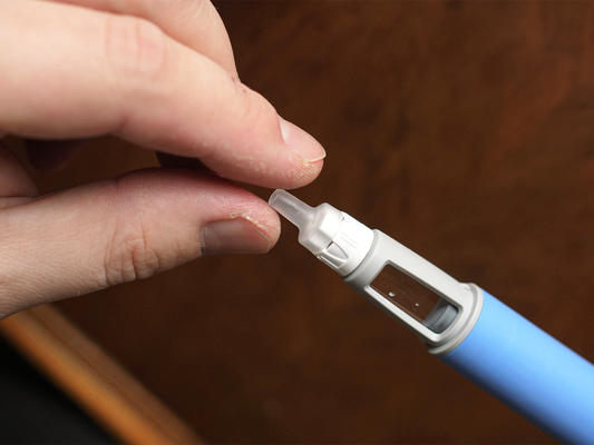 due dita che si stringono attorno all'estremità di una pennetta che contiene il principio attivo dei farmaci per dimagrire